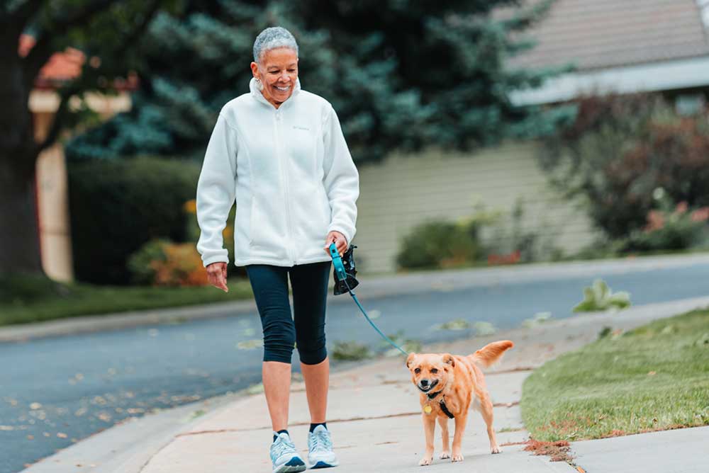 woman walking her dog on the sidewalk