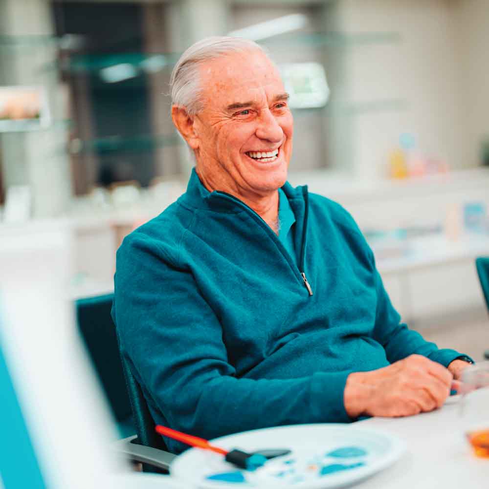 Senior man sitting at table painting